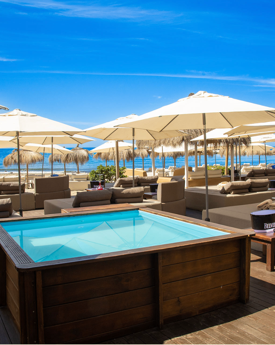 VIP jacuzzi and sunbed area at Kova Beach Club with cream parasols and sea views across the beach