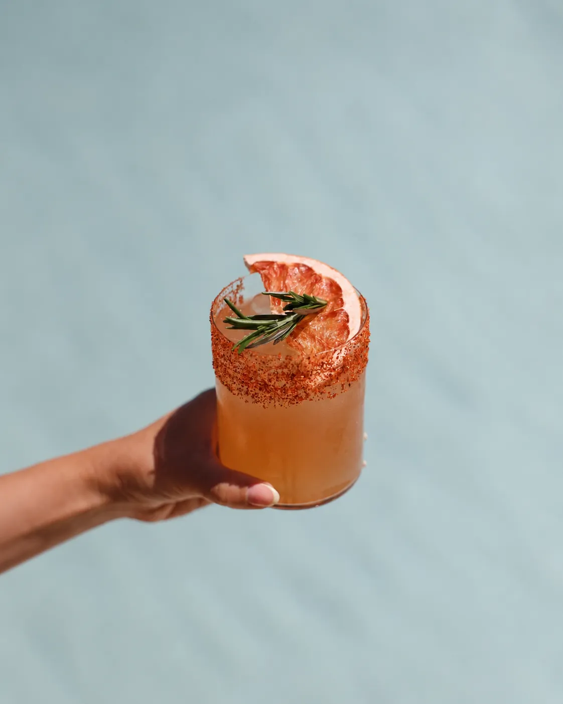 Signature cocktail served at Ocean Club Marbella against a pale blue pool backdrop