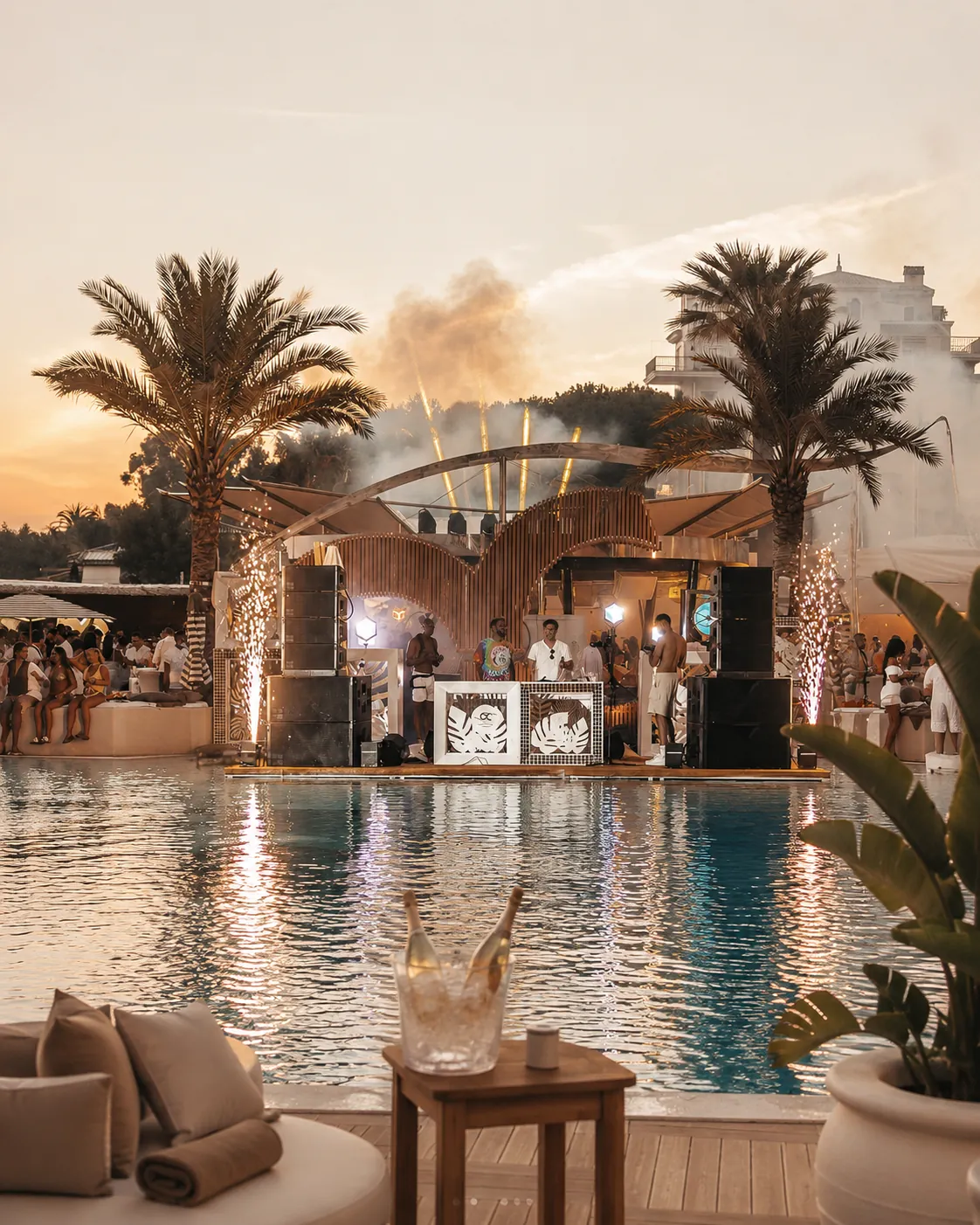 DJ booth and pool party atmosphere at Ocean Club Marbella with pyrotechnics and sunset light