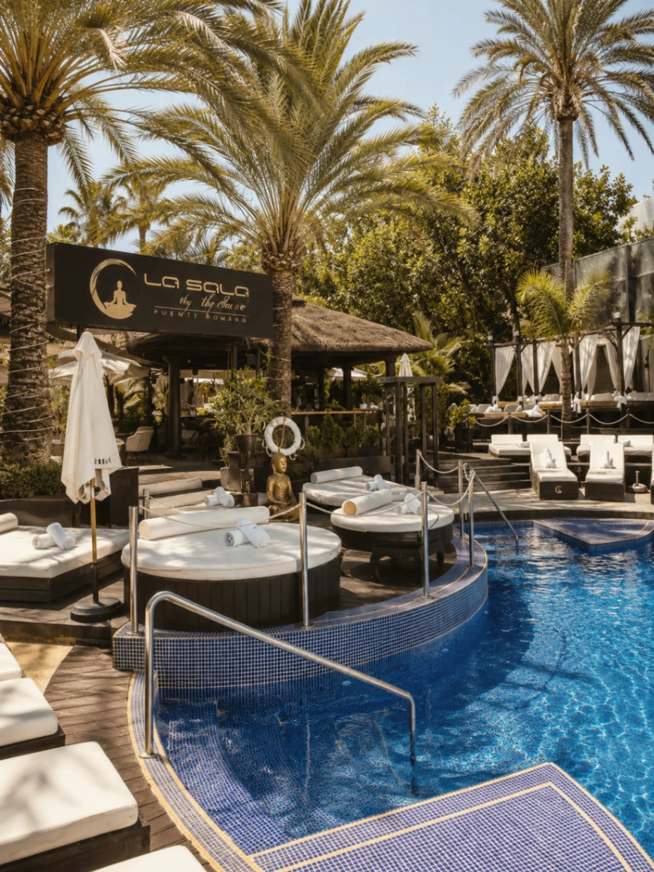 La Sala by the Sea overview with pool, palms, loungers and the entrance sign in Marbella