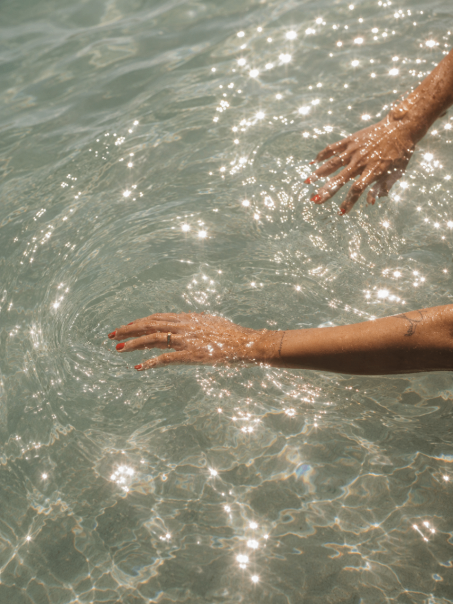 Hands moving through sparkling pool water at Barbillon Marbella