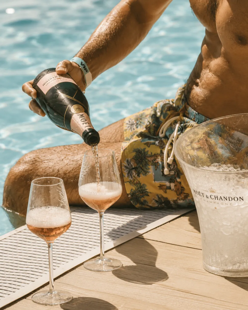 Champagne being poured poolside at Opium Beach Marbella beside an ice bucket and rosé glasses