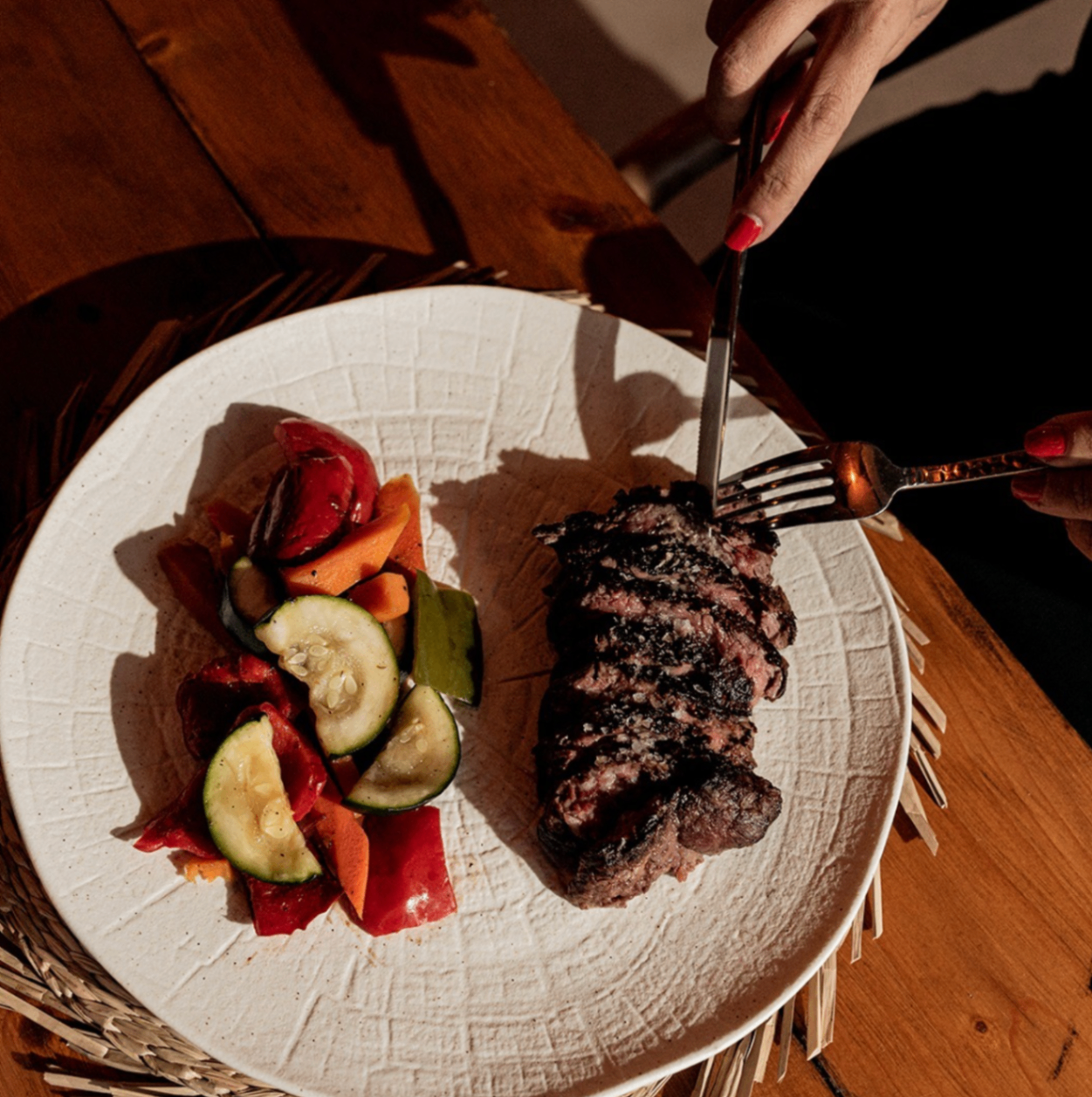 Steak and vegetables served at Alabardero Beach Club on a textured white plate